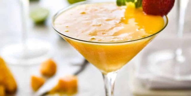 Frozen Mango Daquiris in cocktail glasses, garnished with strawberries.