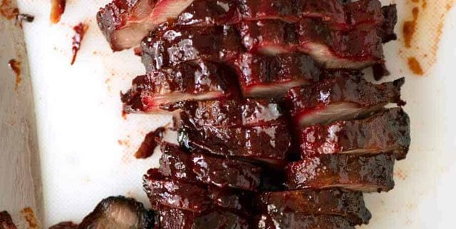 Overhead photo of Char Siu (Chinese Barbecue Pork) sliced on a white cutting board.