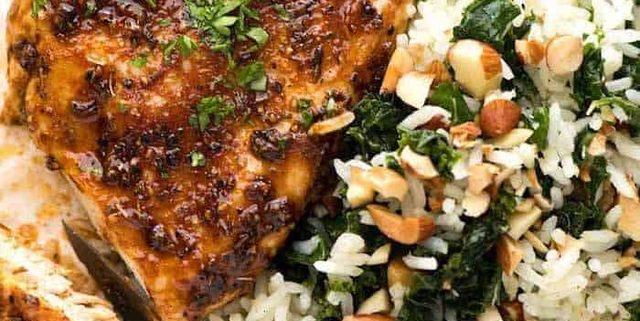 Baked Chicken Breast with a side of Garlic Butter Rice with Kale on a white plate, ready to be eaten.