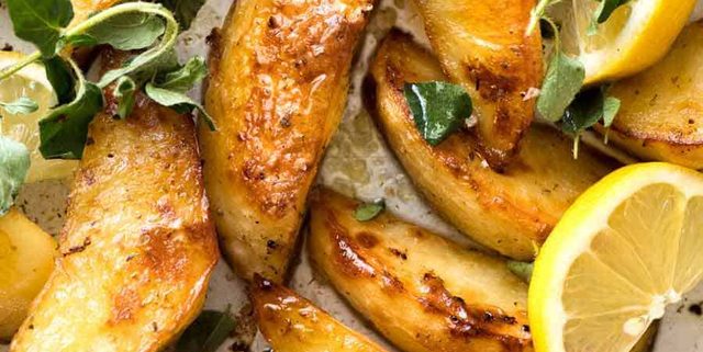 Close up of Greek Lemon Potatoes garnished with fresh oregano and lemon wedges