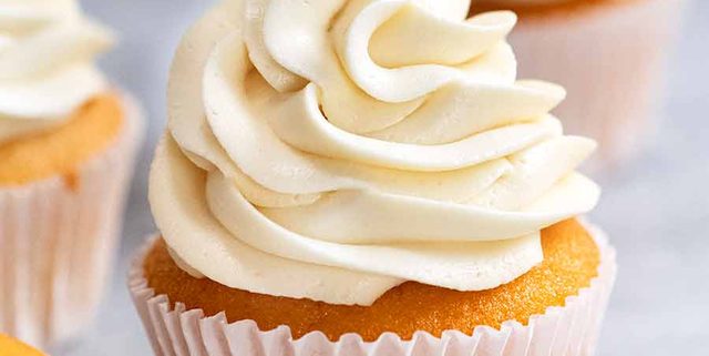 Close up piping Fluffy Vanilla Frosting onto Vanilla Cupcake