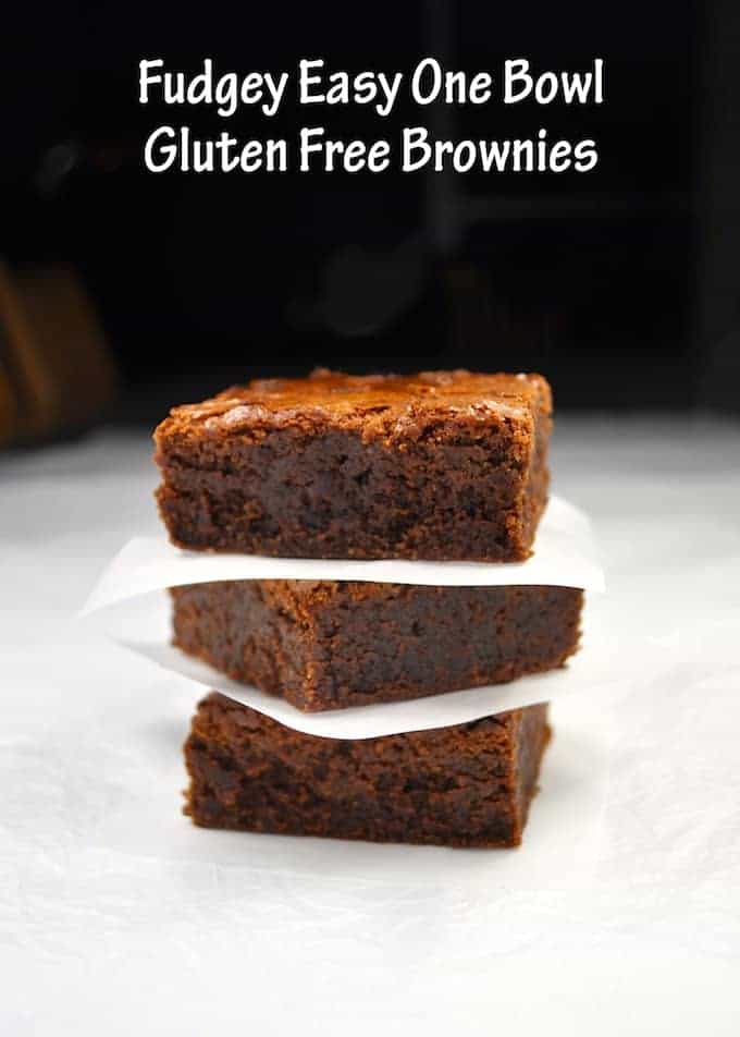 Three Gluten Free Brownies stacked together with baking paper between each slice.