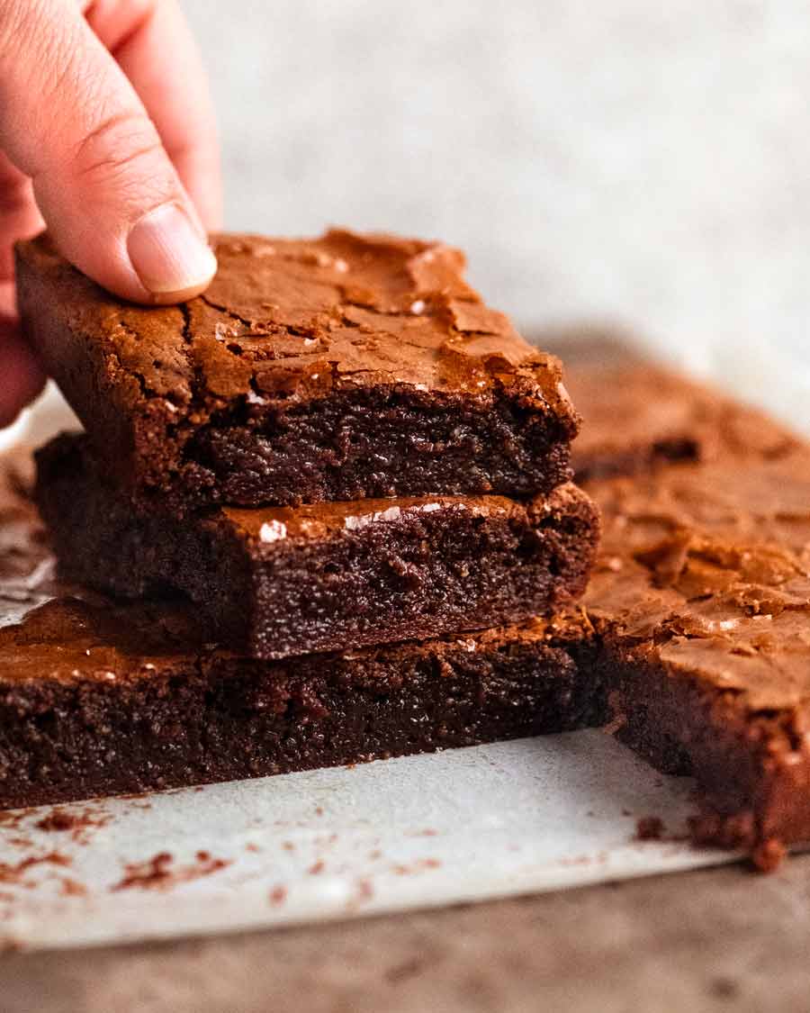 Close up photo of hand picking up a piece of Flourless Chocolate Brownies (gluten free)