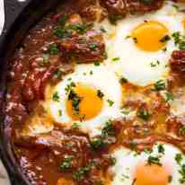 Close up of Shakshuka Middle Eastern baked eggs in a black skillet, fresh off the stove