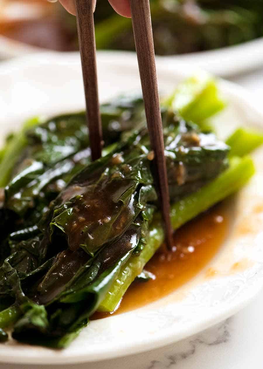 Chopsticks picking up Chinese Broccoli doused with Oyster Sauce 