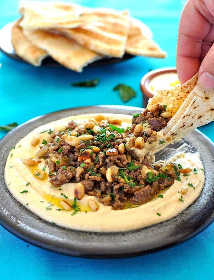 Scooping up hummus and lamb mince with flat bread