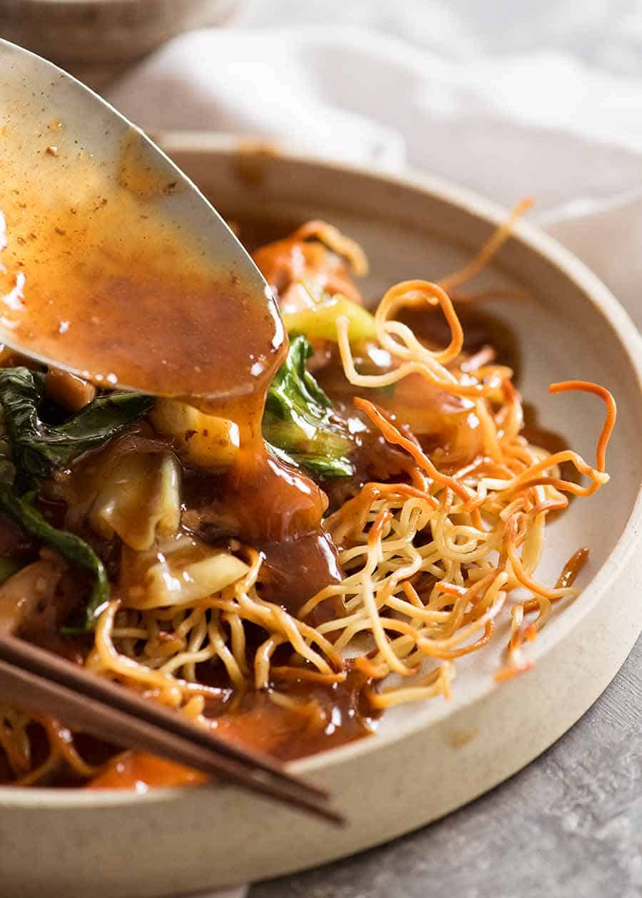 Spooning sauce over Chinese Crispy Noodles (Chow Mein)
