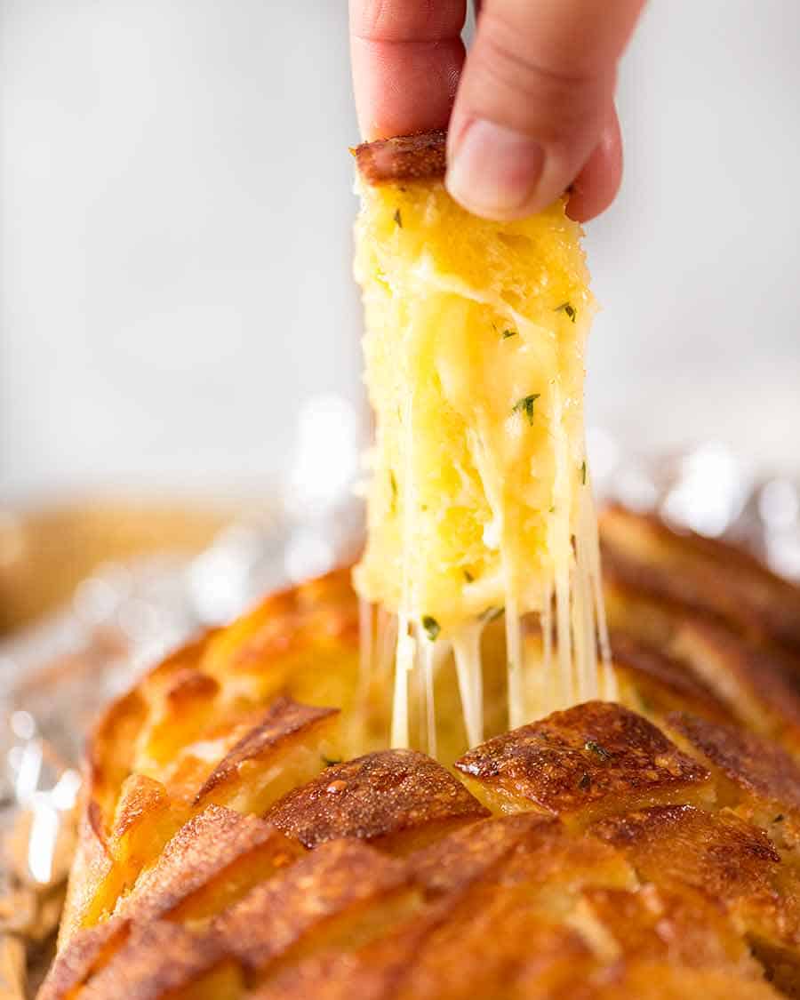 Hand pulling up out a piece of Cheese and Garlic Crack Bread (Cheesy Garlic Pull Apart Bread)