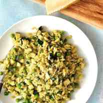Pea, Zucchini and Pesto Orzo / Risoni on a white plate with parmesan on the side.