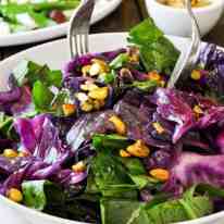 Warm Red Cabbage Salad with Garlic Herb Butter being tossed in a salad bowl.
