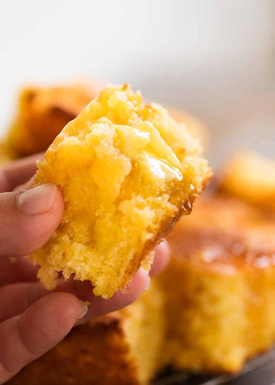 Hand holding a piece of cornbread, showing the inside of the cornbread