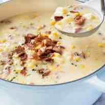 Ham and Corn Chowder in a French casserole pot being ladled out for serving.