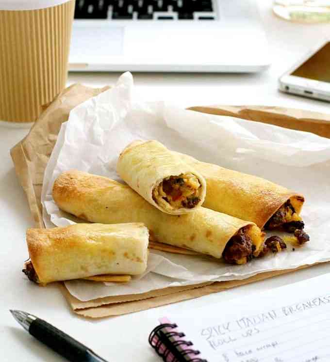 Spicy Italian Breakfast Roll Ups on a work desk with takeaway coffee cup, computer and notebook