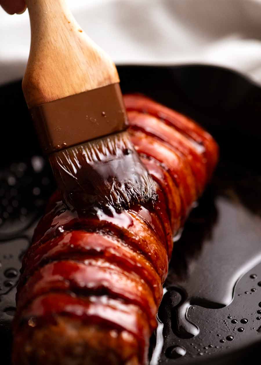 Brushing honey onto Bacon wrapped pork tenderloin
