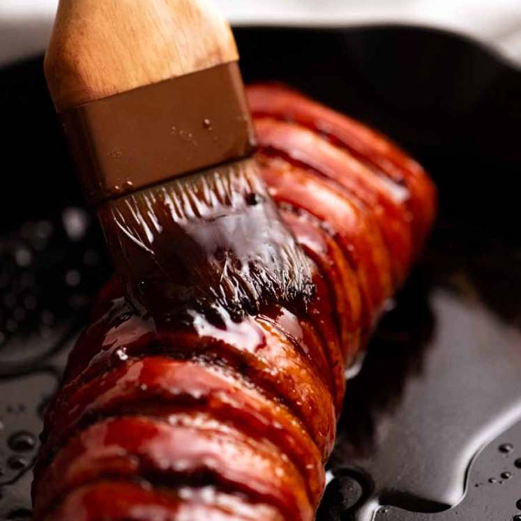 Brushing honey onto Bacon wrapped pork tenderloin
