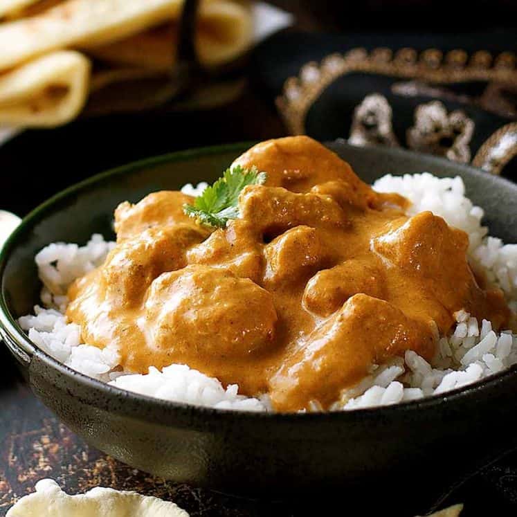 Butter Chicken on rice in a rustic black bowl, ready to be eaten
