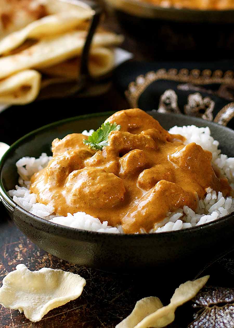 Butter chicken over rice in a rustic black bowl, ready to eat