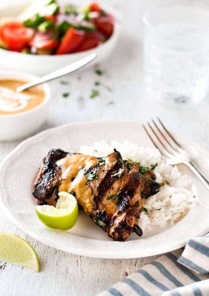 Grilled Coconut Marinated Chicken with a side of lime rice on a white plate, ready to be eaten.