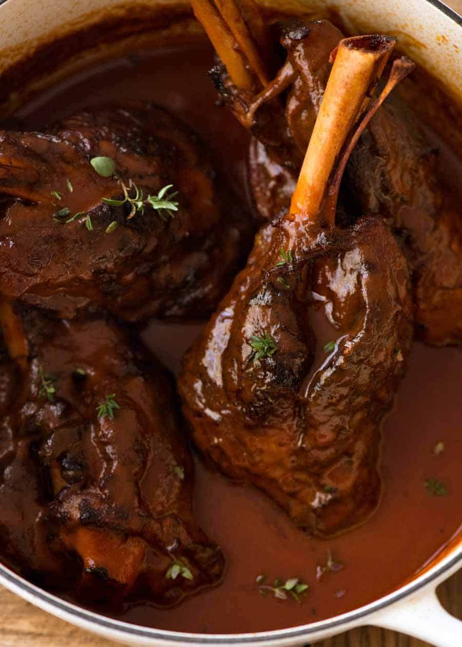 Slow Cooked Lamb Shanks in Red Wine Sauce in a cast iron pot, fresh off the stove ready to be served