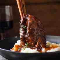 Slow Cooked Lamb Shanks in Red Wine Sauce served on creamy mashed potato, ready to be eaten