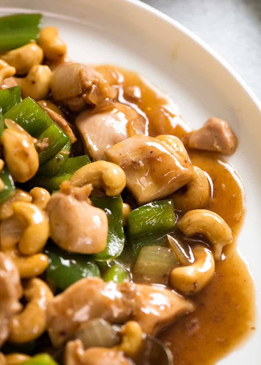 Close up of saucy Chinese Cashew Chicken on a white plate, ready to be served