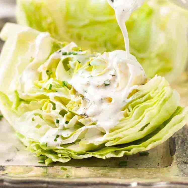 Pouring Ranch Dressing on lettuce wedges for Lettuce Wedge Salad