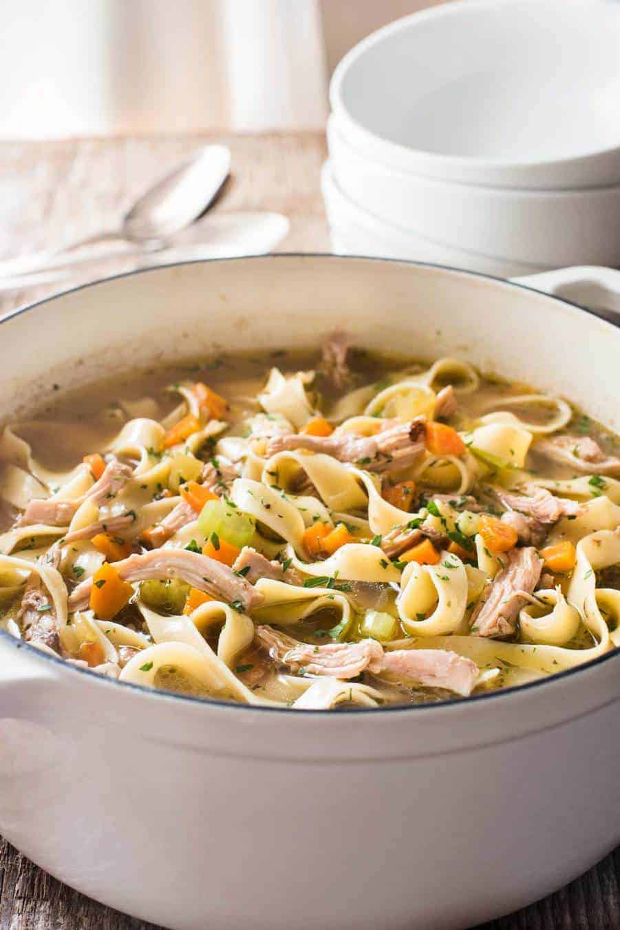 An easy Chicken Noodle Soup in a white cast iron pot, piping hot fresh off the stove.