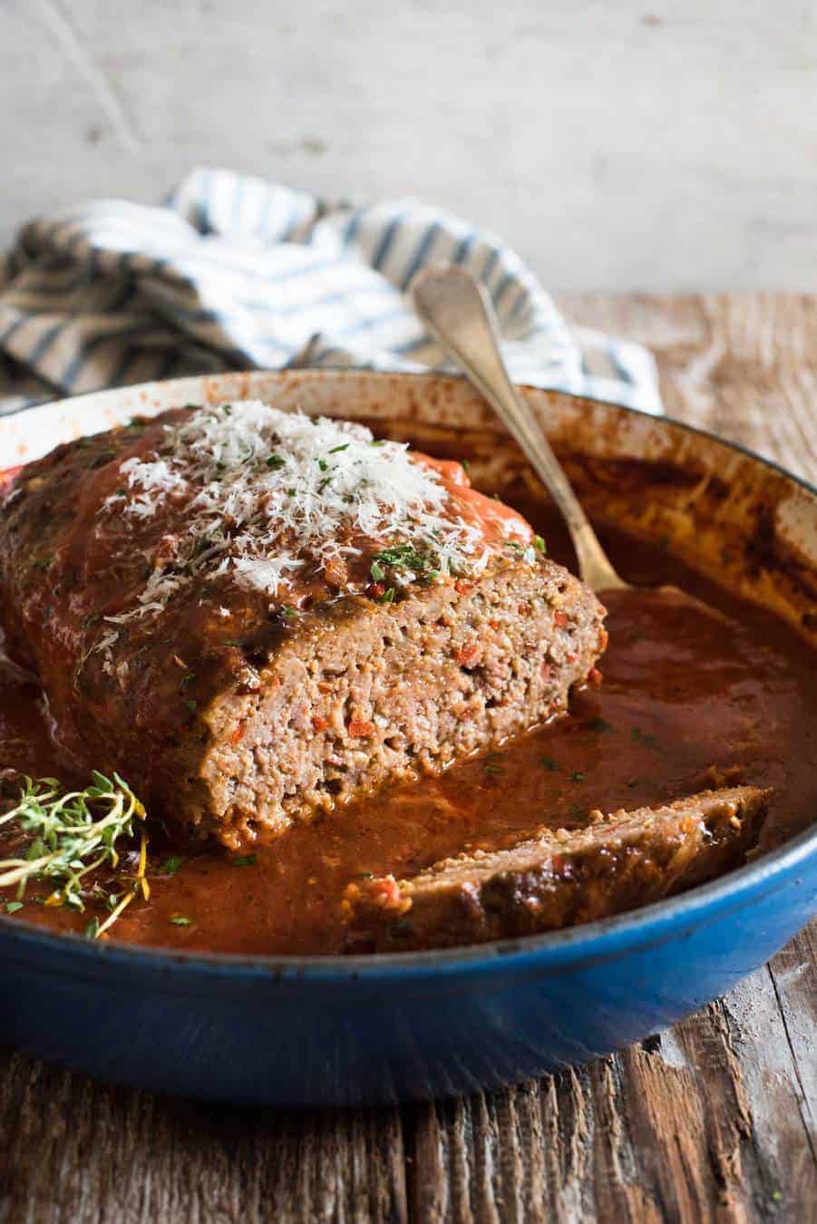 Italian Meatloaf with tomato marinara sauce in a round blue casserole pan with the end sliced off, revealing the juicy inside.