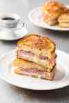 Monte Cristo Sandwich cut in half and stacked on each other on a small white plate, ready to be eaten.