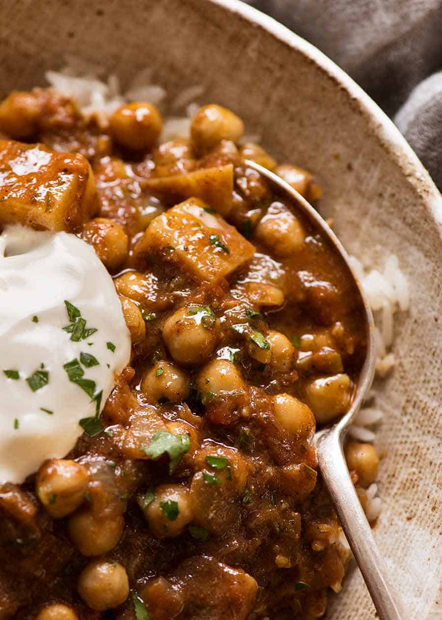 Close up of Chickpea Curry (Chana Aloo) in a bowl over coconut rice with a dollop of yogurt