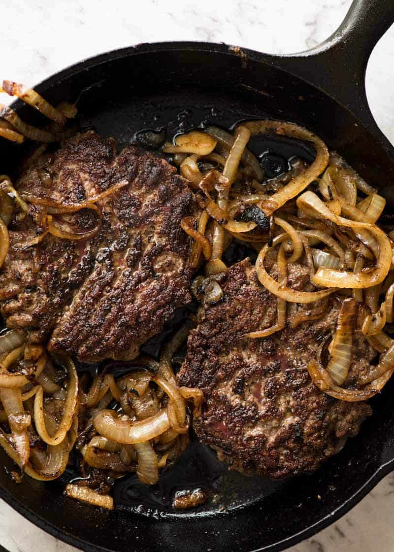Beef Hamburgers in a black skillet, fresh off the stove
