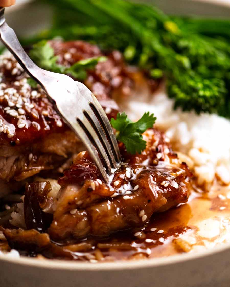 Fork picking up piece of Honey Soy Baked Chicken set on rice