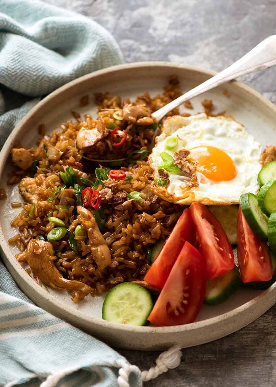 Nasi Goreng on a plate with a side of fried egg, tomato and cucumbers