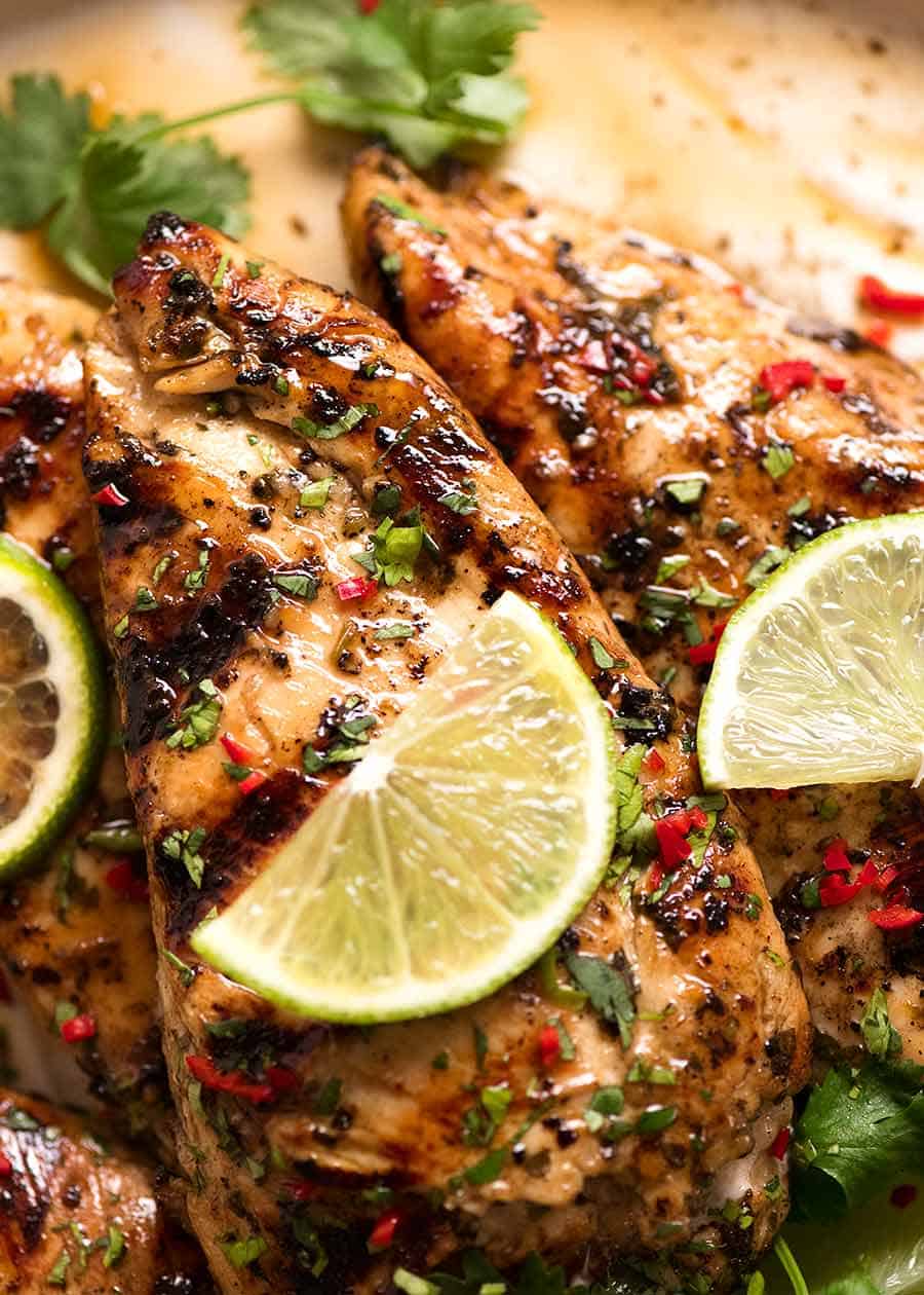 Close up of Lime Chicken on a plate, garnished with cilantro/coriander, chilli and fresh lime slices