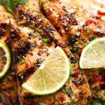 Close up of Lime Chicken on a plate, garnished with cilantro/coriander, chilli and fresh lime slices