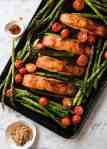 Spicy Brown Sugar Salmon on tray with asparagus and tomatoes