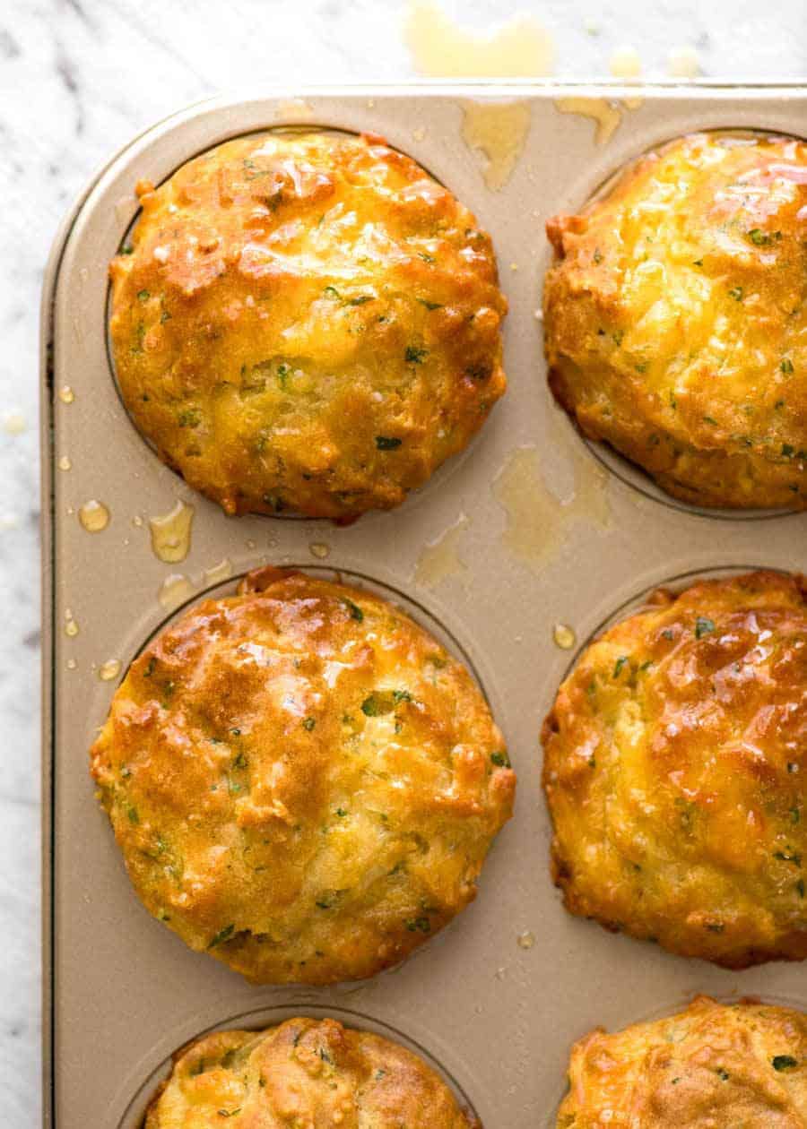 Overhead shot of savory cheesy golden muffins in a golden muffin tin.