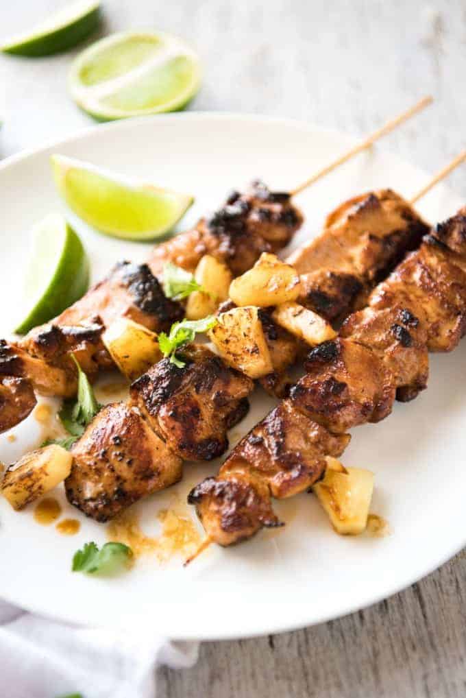 Pineapple Coconut Hawaiian Chicken Skewers on a white plate garnished with caramelised pineapple pieces.