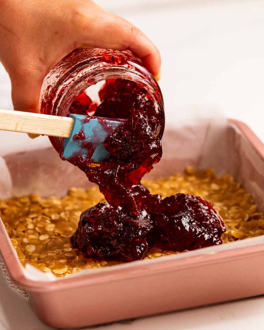 Pouring jam onto Raspberry jam oat bars