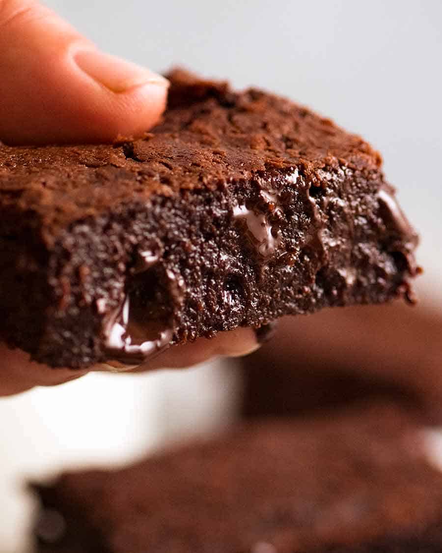 Close up of hand holding super fudgy chocolate brownies