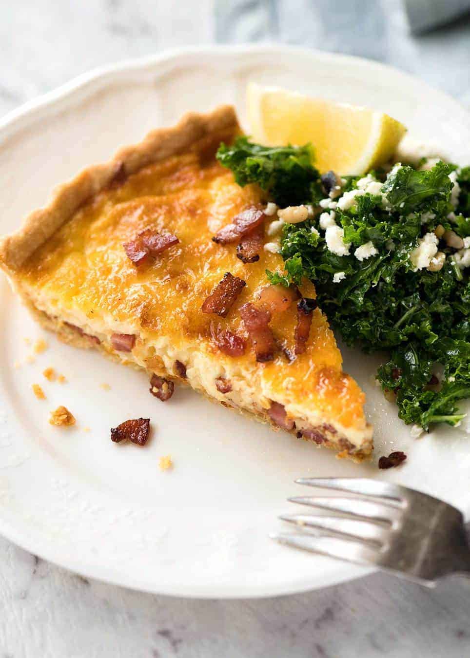 A slice of Quiche Lorraine on a plate, ready to be eaten.