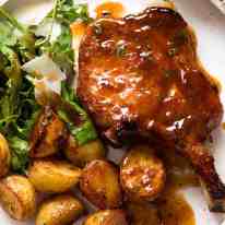 Overhead photo of Oven Baked Pork Chops with potatoes, with a side of Rocket with Parmesan and Balsamic