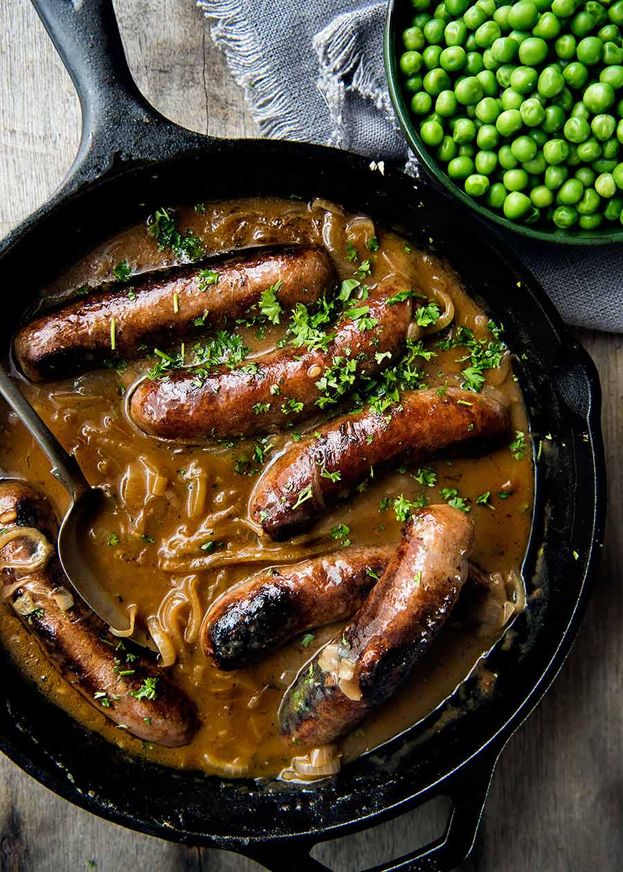 Sausages with gravy in a black skillet, ready to be served