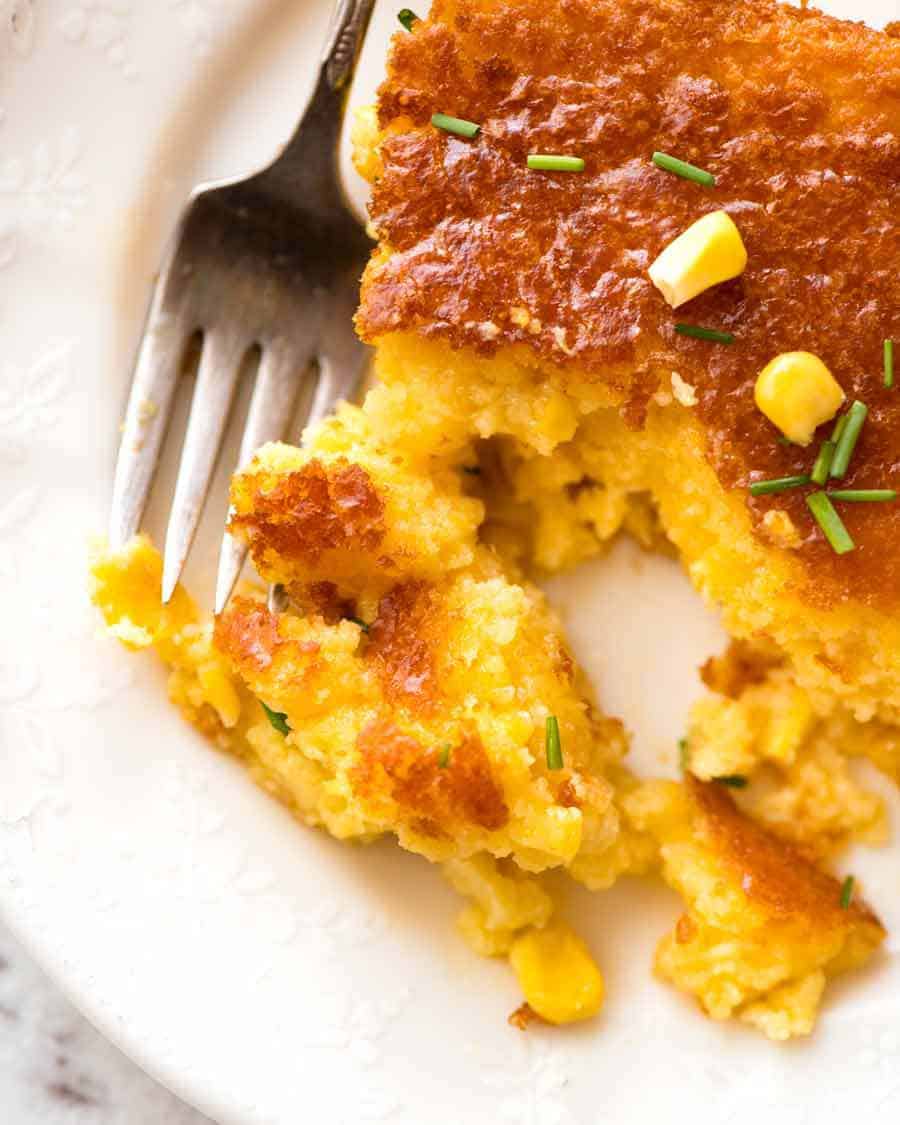 Close up of Corn Casserole on a white plate with a fork