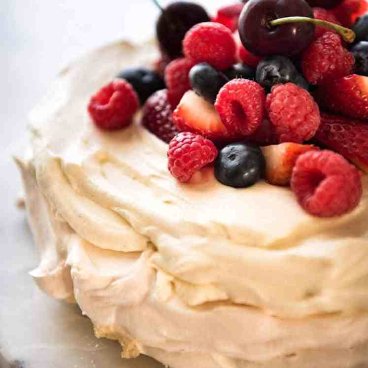 Close up of Pavlova topped with cream and berries