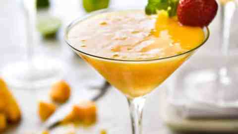 Frozen Mango Daquiris in cocktail glasses, garnished with strawberries.