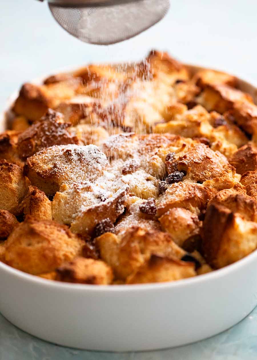 Dusting freshly cooked Bread and Butter Pudding with icing sugar