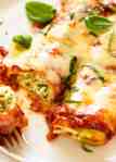 Close up photo of 2 pieces of Spinach and Ricotta Cannelloni with tomato pasta sauce on a plate