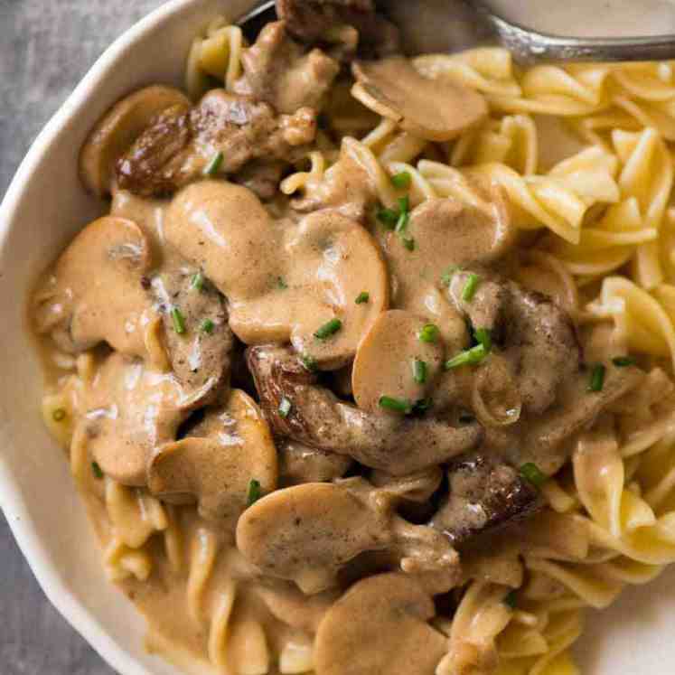 Beef Stroganoff in a rustic white bowl over noodles