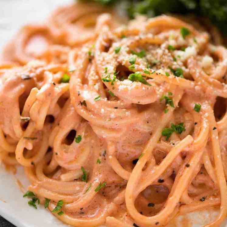 Creamy tomato pasta on a plate with marinated kale salad.
